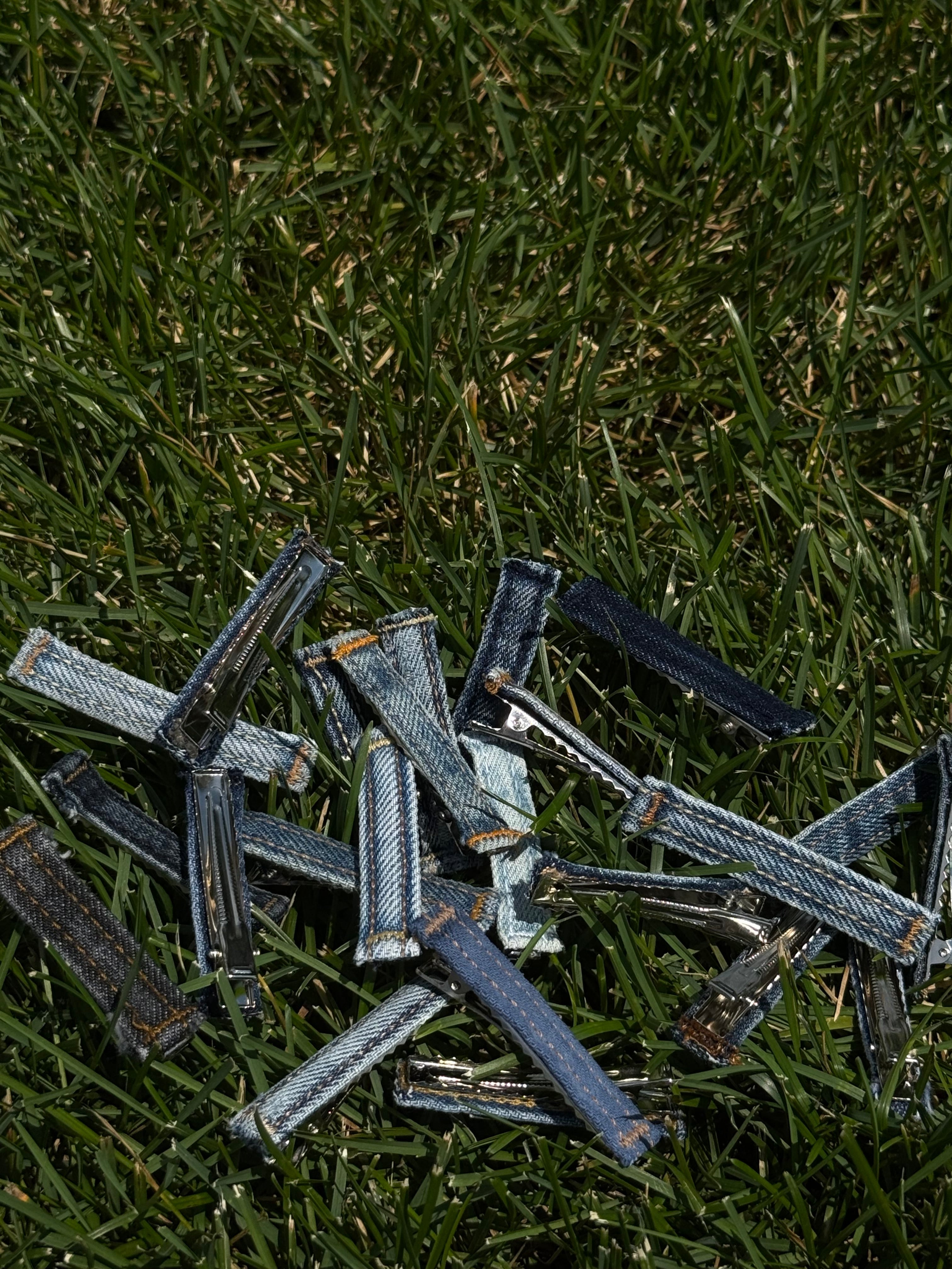 Pile of denim jeans on grass.