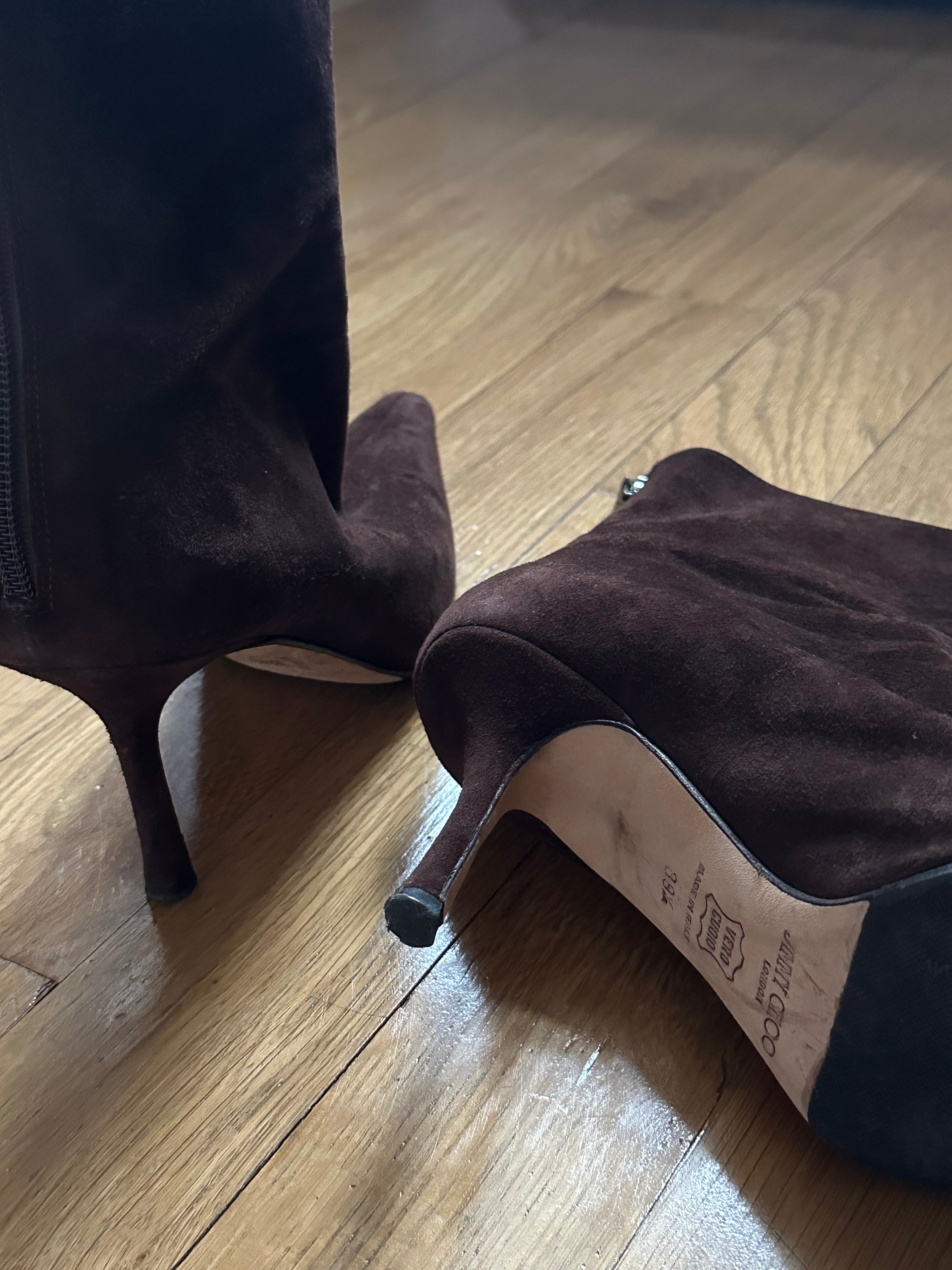 Brown high-heeled boot on a wooden floor.